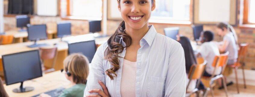 Pretty teacher smiling at camera at back of classroom