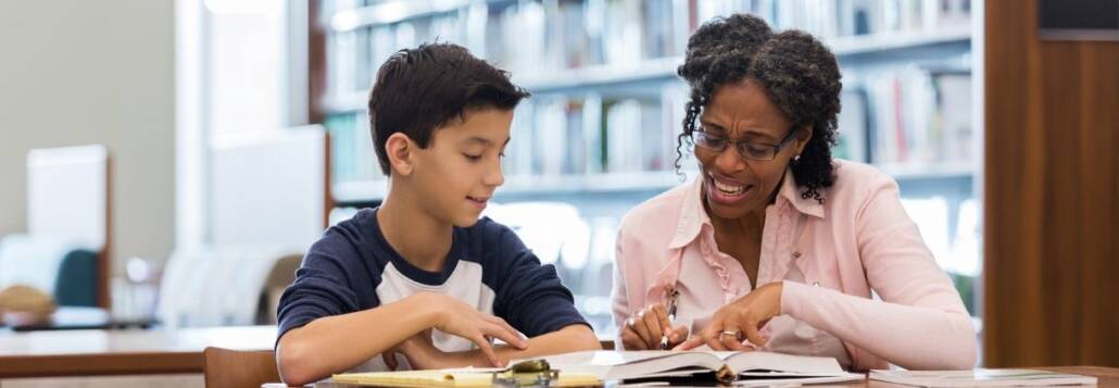 An ADHD coach, passionately pointing to a specific passage in a book, as she imparts knowledge to an engrossed student sitting nearby. The scene captures a key moment of personalized instruction in managing and thriving with ADHD.