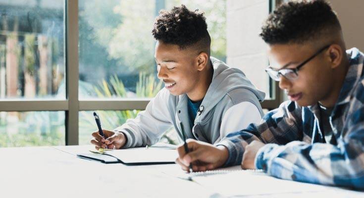 Two black students diligently collaborating on their homework, demonstrating teamwork and commitment to their academic growth.