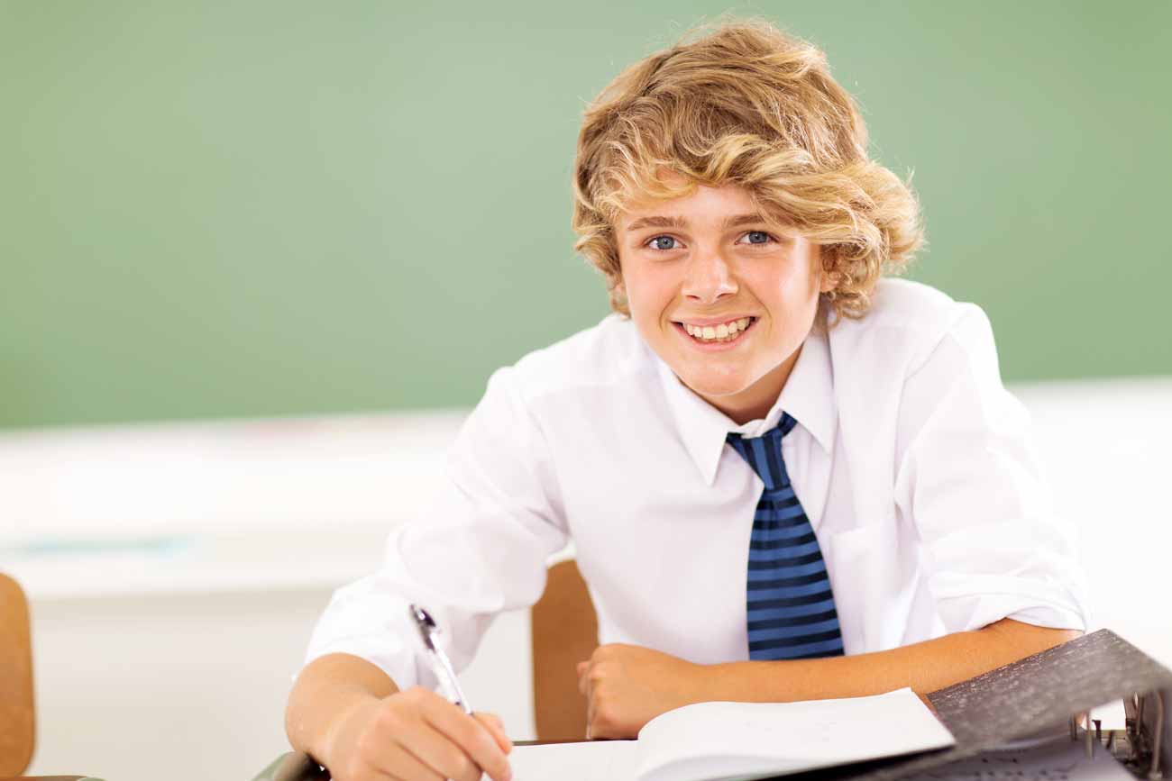 Young student with curly blonde hair intently focusing on coursework, immersed in academic study.