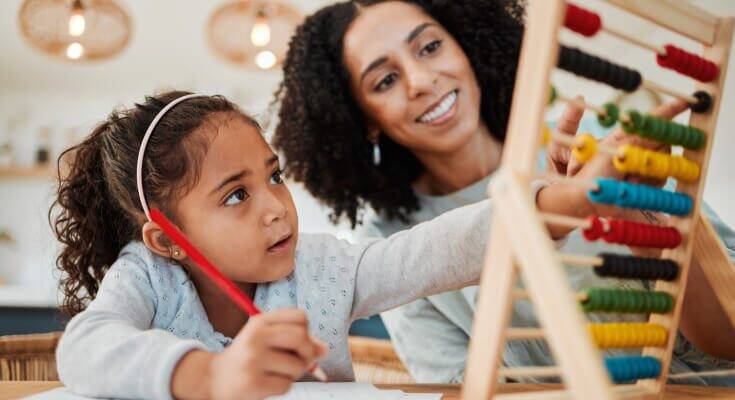 Elementary school female student and an adult work together counting on an abacas 