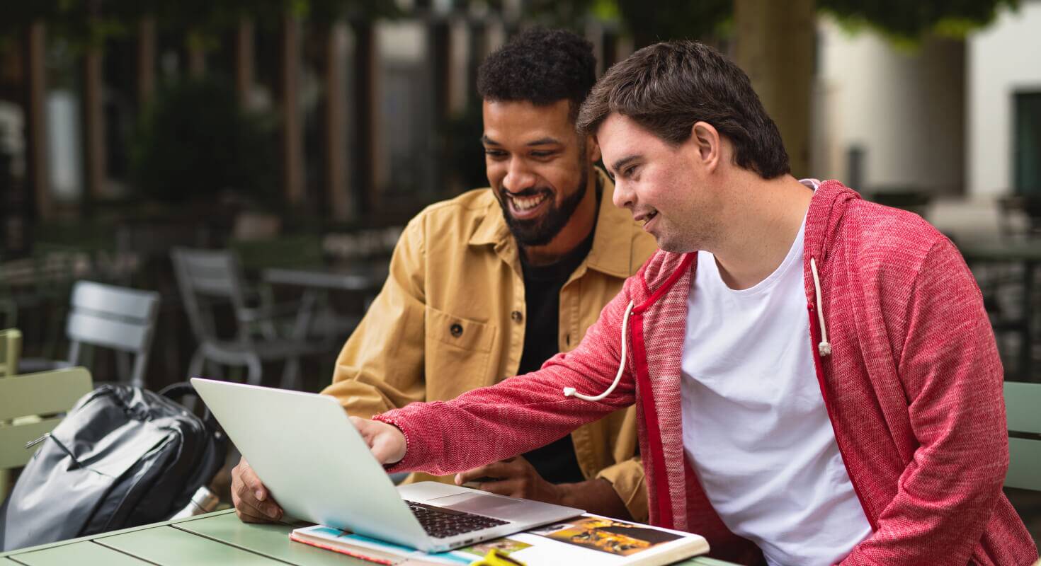 Two high school male students sit together in front of a laptop participating in a peer mentoring program. 