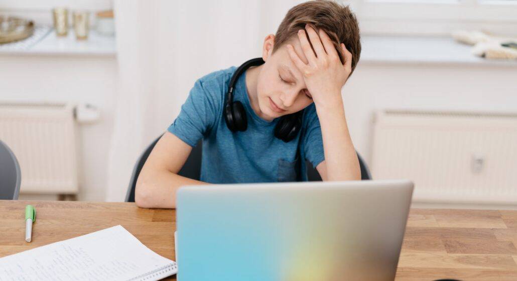 A student looks overwhelmed while sitting in front of a laptop